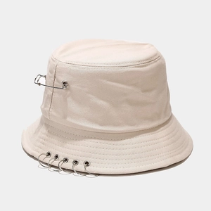 Détail du chapeau bob en toile avec cinq anneaux argentés et une épingle de sûreté