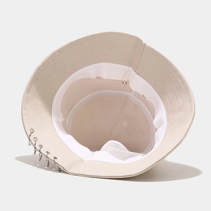 Détail d'un chapeau bob beige avec cinq anneaux argentés et une doublure en maille aérée