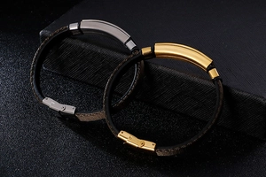 Detail of silver and gold heartbeat charms on black braided leather couple bracelets