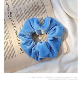 Close-up of blue velvet scrunchie on vintage newspaper with a premium soft texture