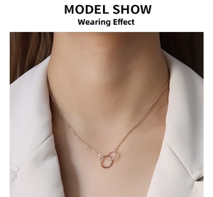 Elegant rose gold double interlocking circle necklace worn by a model in a white blazer