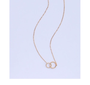 Detail showing interlocking gold circles pendant with twisted texture on a purple background