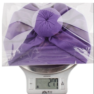 Gewichtsmessung des lila Turban-Huts zeigt 27,7g auf einer digitalen Waage
