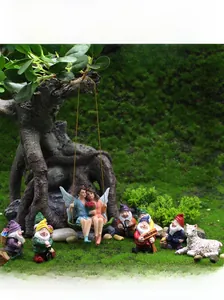 Macro detail of resin flower fairy couple on swing and miniature garden gnomes