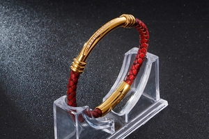 Detail of red braided leather bracelet with gold metal bar and sparkling zircons