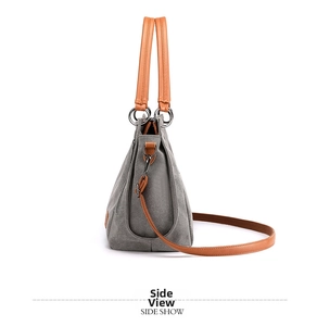 Side view of gray canvas bag with brown leather straps and metal ring details