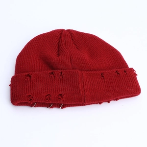 Detail of red distressed knit beanie with silver metal rings and street style texture