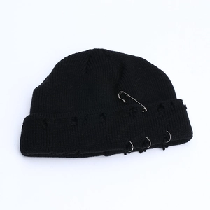 Detail of black knit beanie featuring punk distressed holes and silver safety pin rings