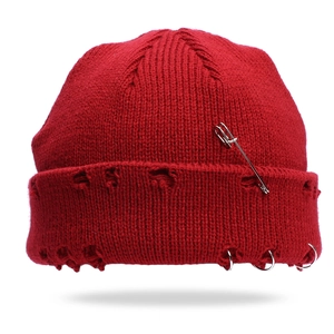 Close-up of red distressed knit beanie featuring punk metal rings and a large safety pin