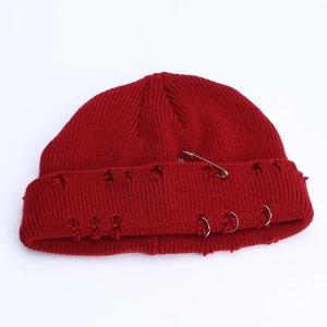 Close-up of dark red distressed knit beanie with silver safety pin and metal rings