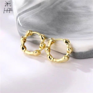 Minimalist gold brass hoop earrings with irregular hammered texture on marble backdrop
