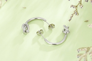 Détail de boucles d'oreilles nœuds en acier inoxydable argenté sur fond texturé