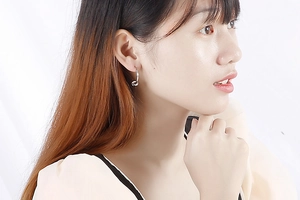 Gros plan de boucles d'oreilles créoles nouées en argent montrant le design sur un mannequin
