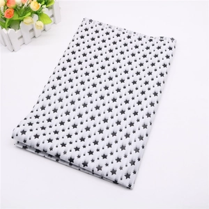 Detail of folded tissue paper featuring black star patterns for gift wrapping decor