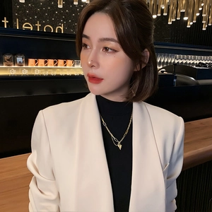 Détail d'un collier pendentif cœur doré sur un mannequin dans un cadre intérieur chic