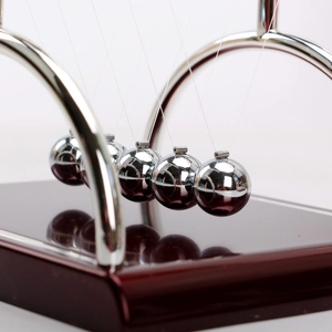 Macro detail of polished Newton's cradle balance balls with chrome finish on wooden base