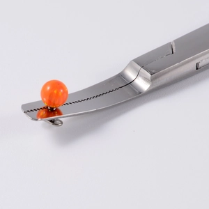 Stainless steel body piercing tweezers holding an orange opal bead on white background