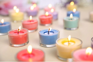 Close-up of multicolored scented candles in glass containers with warm candlelight glow