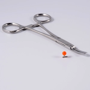 Detail of stainless steel piercing forceps with orange opal skin anchor jewelry set