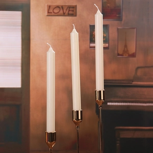 Three white taper candles on gold metal holders for romantic dinner and home decor