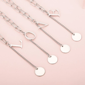 Minimalist silver stainless steel letter necklaces L-O-V-E on soft pink background