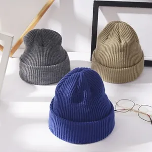 Close-up of ribbed knit beanies in grey, khaki, and royal blue showing thick yarn texture