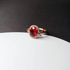Detail of rose gold plated ring with oval ruby red crystal and heart side accents