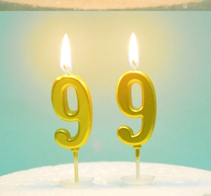 Close-up of burning gold number 9 birthday candles with warm flame on blue background