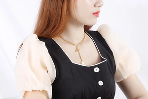 Detail of gold link chain necklace featuring a bold letter A pendant and small round tag