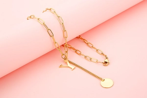 Detail view of gold paperclip chain necklace with letter Y and round disc pendants