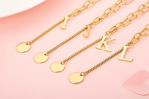 Detailed view of four golden letter necklaces I, J, K, L with stylish mixed link chains