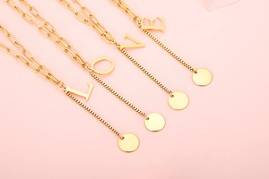 Detail view of gold letter pendants L O V E on stylish stainless steel necklaces