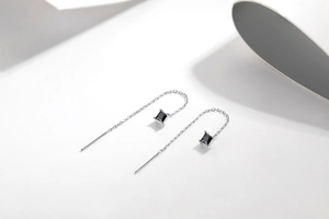 Detail view of S925 silver chain earrings with square black gemstone on white background