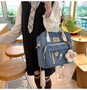 Blue canvas crossbody bag detail showing cute cartoon pins and plush flower charm accessory
