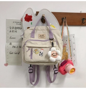 Detail of canvas shoulder bag featuring a plush flower charm and cute milk badges