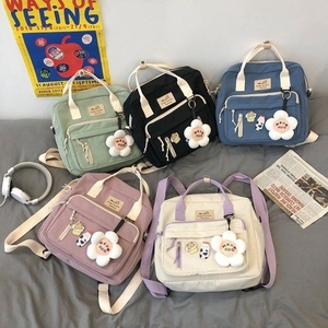 Flat lay of canvas backpacks in black, beige, blue, green and purple with cute floral charms