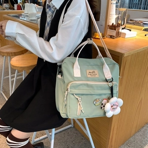 Detail of light green canvas backpack featuring a front zipper pocket and top handles