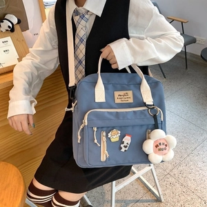 Blue canvas crossbody bag detail with cute cartoon badges and a plush flower charm