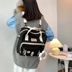 Detail of black canvas backpack with contrast straps and cute flower plush charm pendant