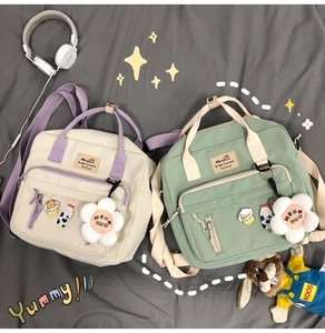 Detail of canvas messenger bag with cartoon patches and daisy plush charm accessory