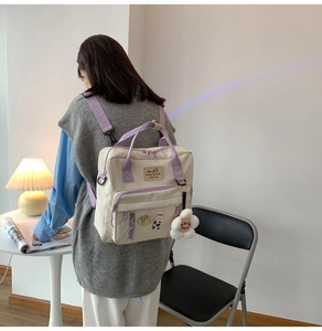 Detailed view of the off-white canvas backpack worn by a model in a minimal studio setting