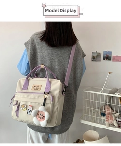Detail view of cream and purple canvas bag with cute bear pins and floral plush charm