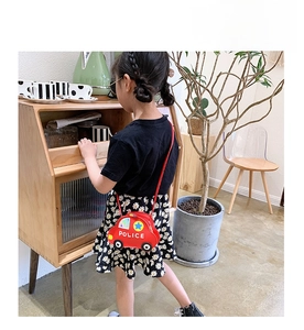 Detail view of the red police car shaped shoulder bag worn by a child in a home setting