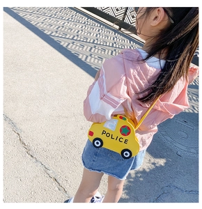 Outdoor shot of a child wearing a yellow police car shaped mini crossbody shoulder bag