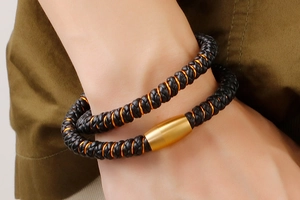 Gros plan d'un bracelet double en cuir noir avec un fermoir magnétique en or mat au poignet
