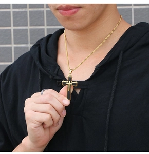 Close-up of men's gold and black cross pendant necklace worn with a gold rope chain