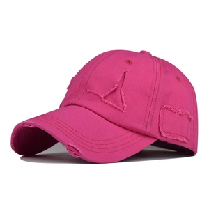 Close-up of bright pink distressed baseball cap with ripped fabric details and worn texture
