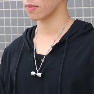 Macro shot of silver dumbbell pendant on a twisted chain necklace worn by a male model
