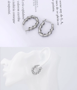 Close-up of vintage punk style braided thorn hoop earrings for men in silver finish
