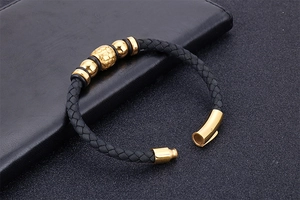 Detail of black braided leather men's bracelet with gold metal beads and magnetic clasp